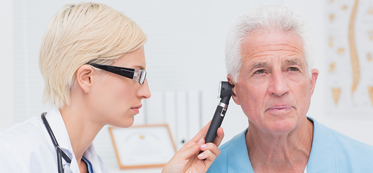 hearing loss - Female doctor examining male patients ear with otoscope in clinic