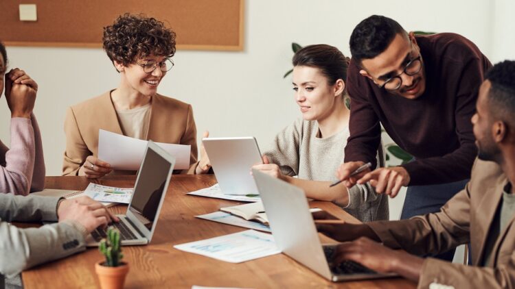 group of business professionals sitting in a meeting room with laptops and paper