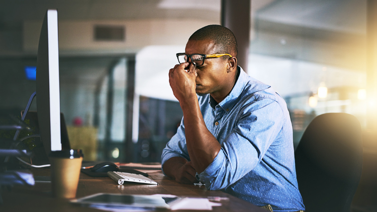 Shot of a young businessman experiencing stress during late night at work